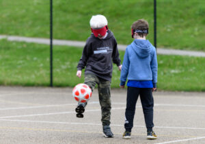 Two boys with visual impairments playing football.